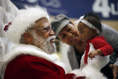 African American Santa Claus Langston Patterson (L), 77, greets four-month-old Raelyn Price as her grandmother Gloria Boissiere looks on, at Baldwin Hills Crenshaw Plaza mall in Los Angeles, California, December 16, 2013. REUTERS/Lucy Nicholson