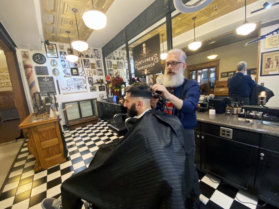 The Gentlemen's Barbershop Prohibition-era decor includes an ancient wooden barbershop pole, historic pictures, a tin ceiling and a black-and-white tile floor.