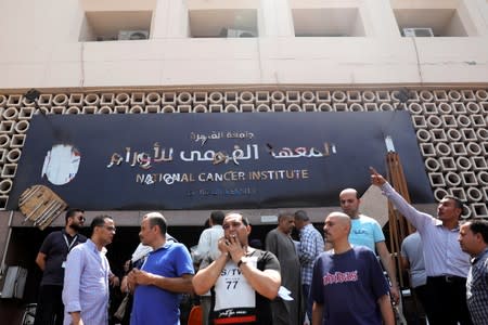 Security guards and relatives of patients are seen at the entrance of the National Cancer Institute after an overnight fire from a blast, in Cairo