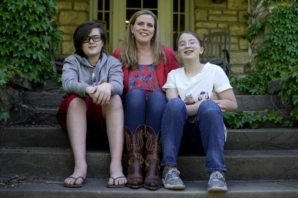 Heather Ousley sits with her older children Elliannah, 15, right, and Samuel, 13, in front of their home in Merriam, Kan, Tuesday, May 4, 2021. Ousley was thrilled when she heard the FDA was expected to authorize Pfizer's COVID-19 vaccine for youngsters ages 12 to 15 and was hoping to get her kids vaccinated as soon as she can. (AP Photo/Charlie Riedel)