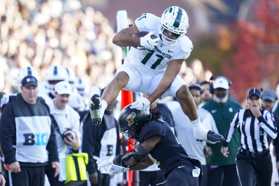 Michigan State running back Connor Heyward (11) leaps over Purdue safety Marvin Grant (4) during the first half of an NCAA college football game in West Lafayette, Ind., Saturday, Nov. 6, 2021. (AP Photo/Michael Conroy)