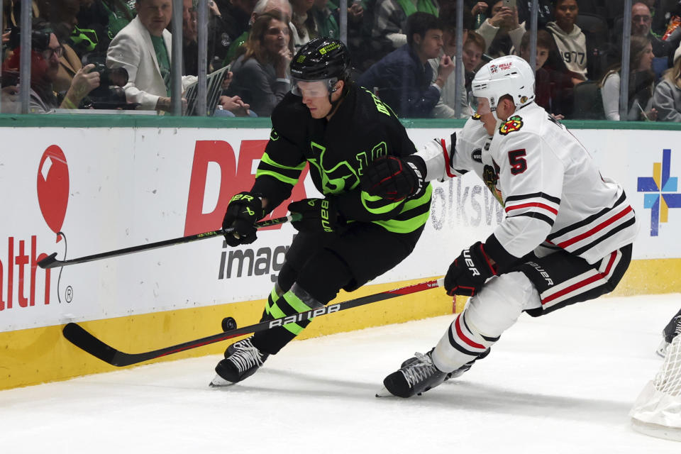 Dallas Stars center Ty Dellandrea and Chicago Blackhawks defenseman Connor Murphy (5) chase the puck behind the goal in the first period of an NHL hockey game Sunday, Dec. 31, 2023, in Dallas. (AP Photo/Richard W. Rodriguez)