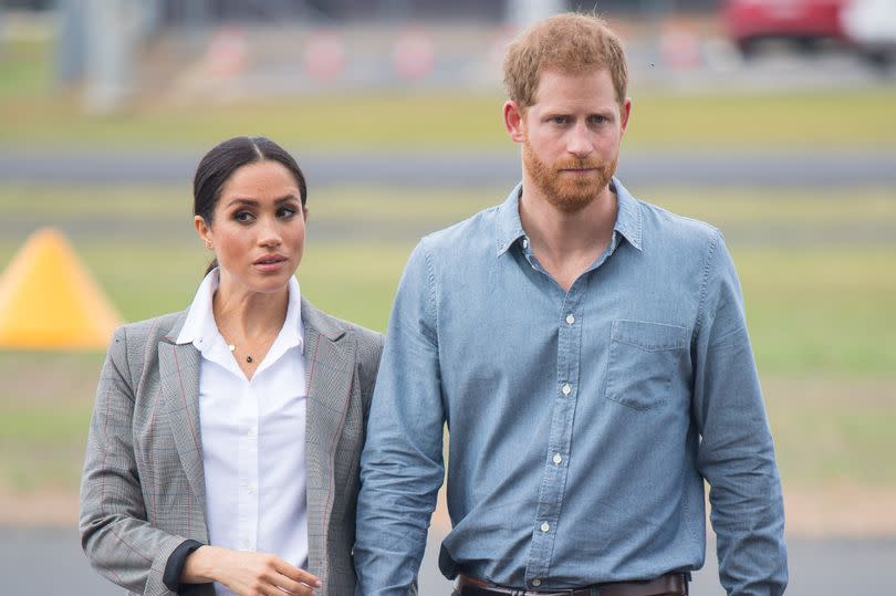 Prince Harry and Meghan Markle look serious as they walk holding hands during 2018 tour of Australia