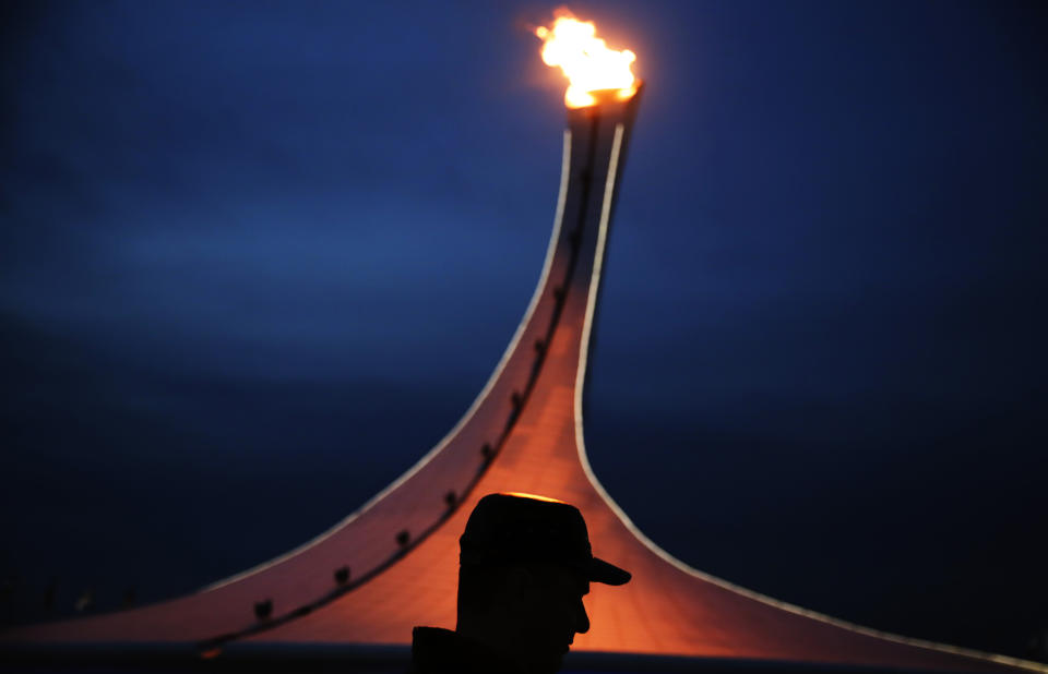 A visitor to the Olympic Park is silhouetted while walking past the Olympic cauldron at the 2014 Winter Olympics, Feb. 20, 2014, in Sochi, Russia.