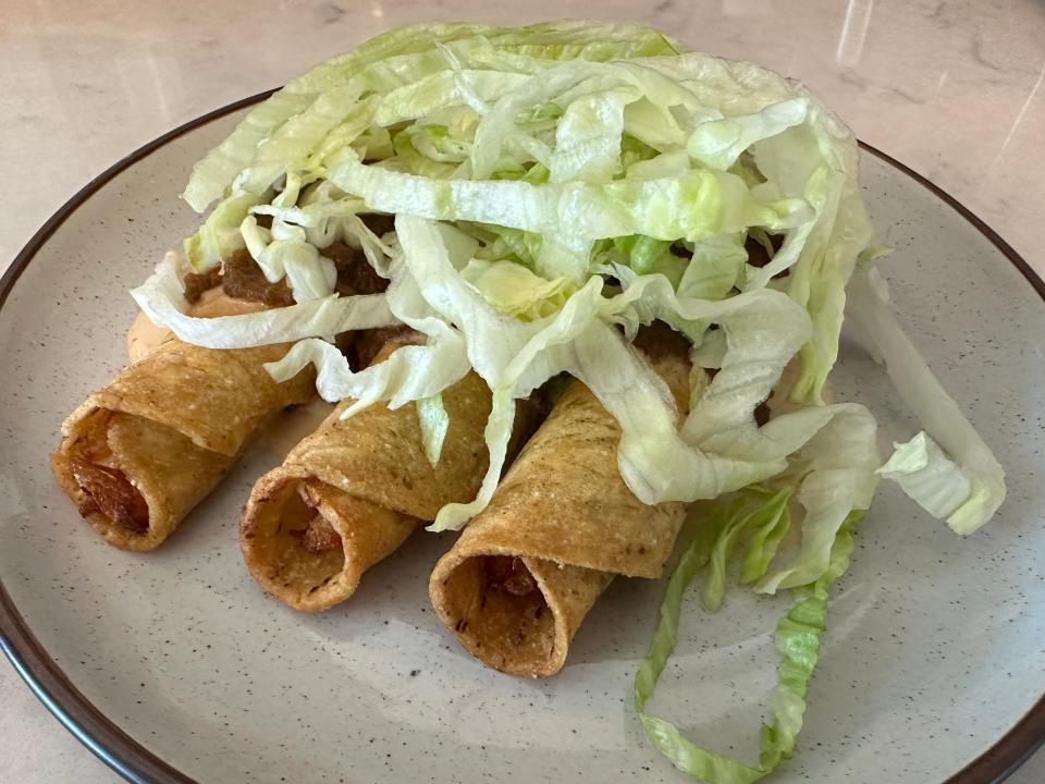 plate of taquitos topped with shredded lettuce