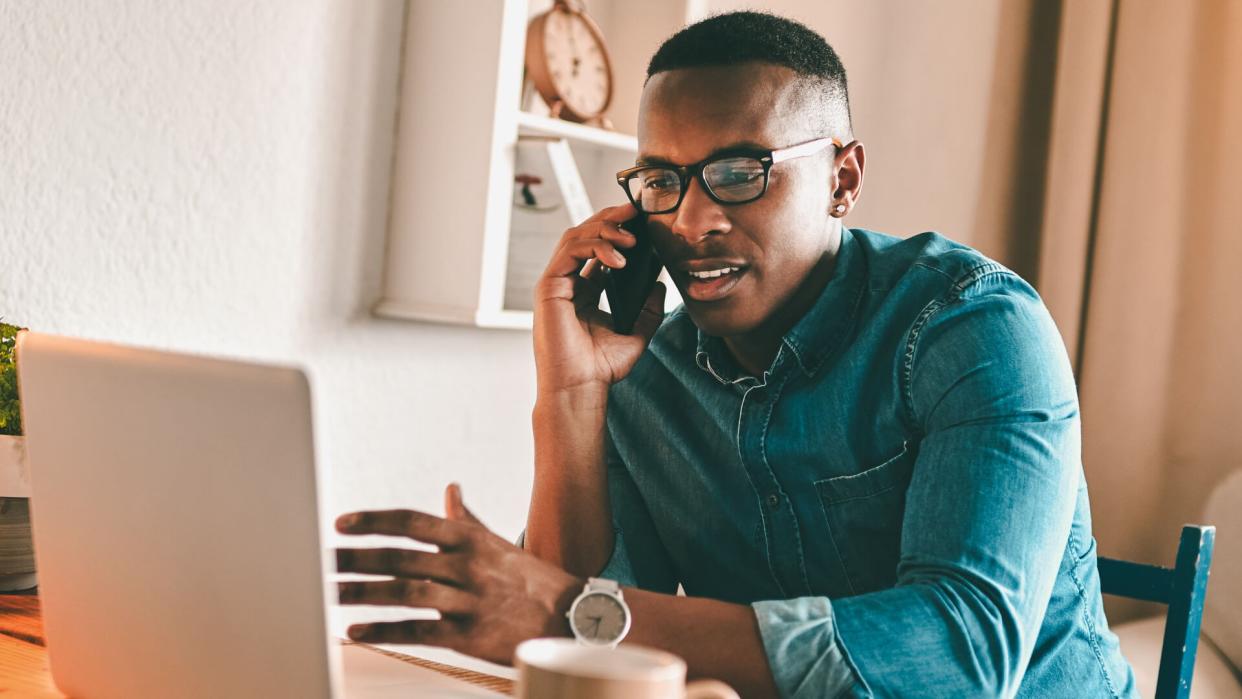 Cropped shot of a handsome young businessman sitting alone in his home office and talking on his cellphone.