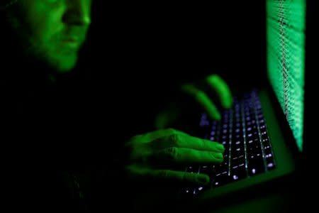 A man types on a computer keyboard in front of the displayed cyber code in this illustration picture taken on March 1,  2017. REUTERS/Kacper Pempel/Illustration