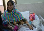 A Pakistani woman sits with her son -- who was wounded by mortar shells allegedly fired by Indian troops -- as he rests at a military hospital in the eastern city of Sialkot, on October 8, 2014