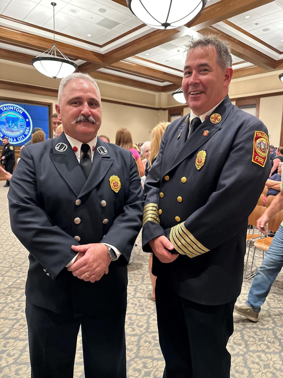 Retiring Taunton Fire Chief Timothy Bradshaw, right, passes the baton to brand new Taunton Fire Chief Steven Lavigne, left, and Lavigne's swearing-in in the City Council chambers on Tuesday, Aug. 8, 2023.