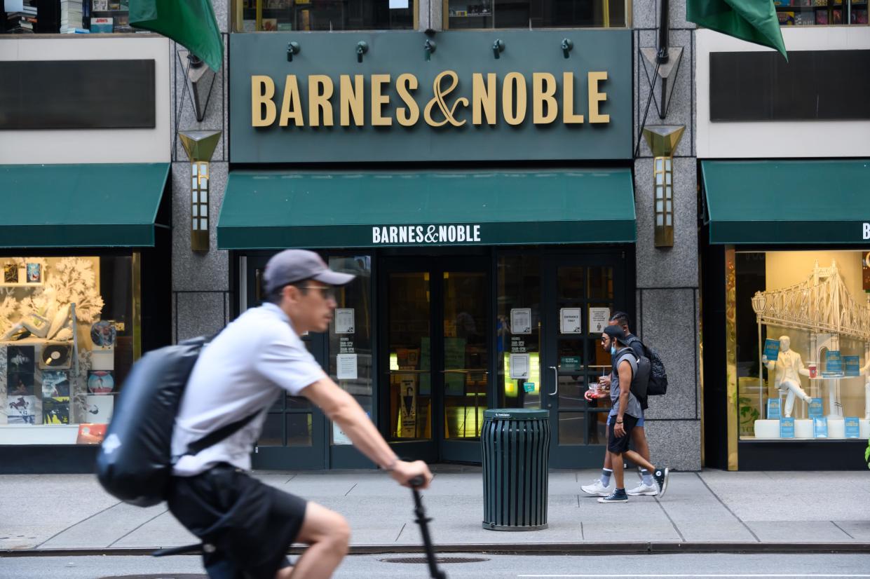 A person cycling in front of a Barnes & Noble bookstore