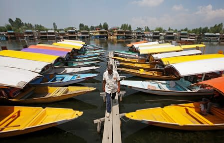 A boatman walks past the parked 'Shikaras' or boats for tourists on the banks of Dal Lake in Srinagar