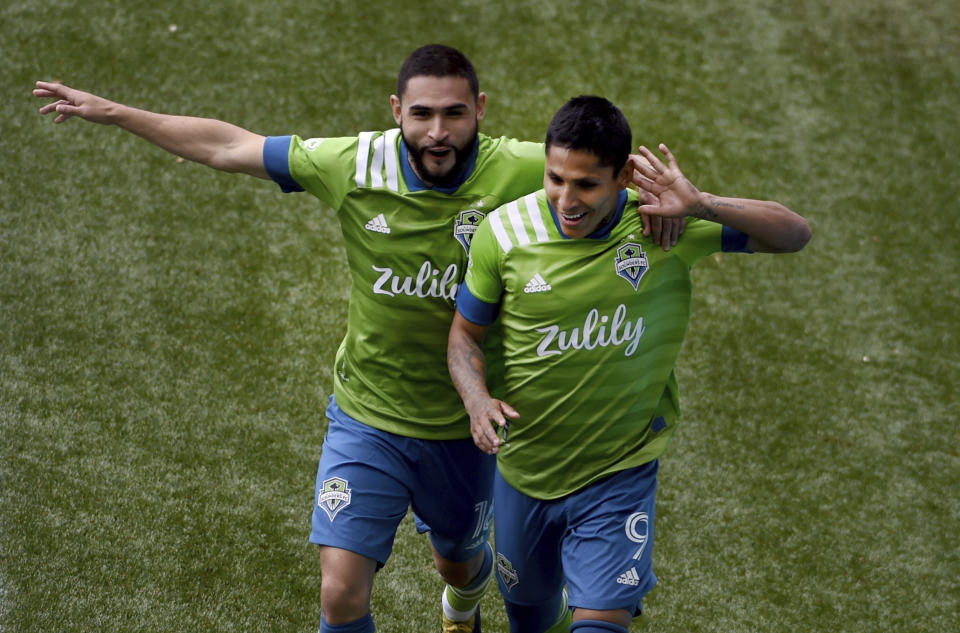 Seattle Sounders forward Raul Ruidiaz, right, celebrates with midfielder Alex Roldan, left, after scoring during second half of an MLS soccer match against the Portland Timbers in Portland, Ore., Sunday, May 9, 2021. (AP Photo/Steve Dykes)