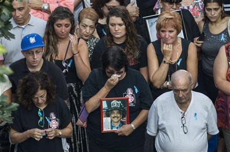 A woman holds a picture of a fire fighter during memorial ceremonies marking the 12th anniversary of the 9/11 attacks on the World Trade Center in New York September 11, 2013. REUTERS/Andrew Burton/Pool