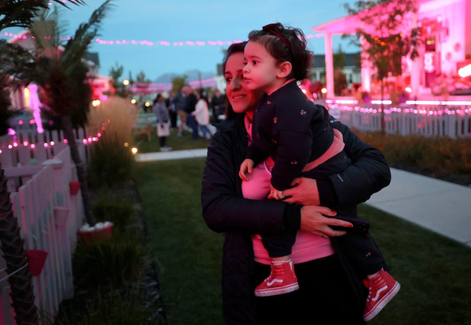 Lily Basile holds Beatriz Basile as they look at houses in a Daybreak neighborhood decorated in a Barbie theme for Halloween in South Jordan on Friday, Oct. 13, 2023. | Kristin Murphy, Deseret News