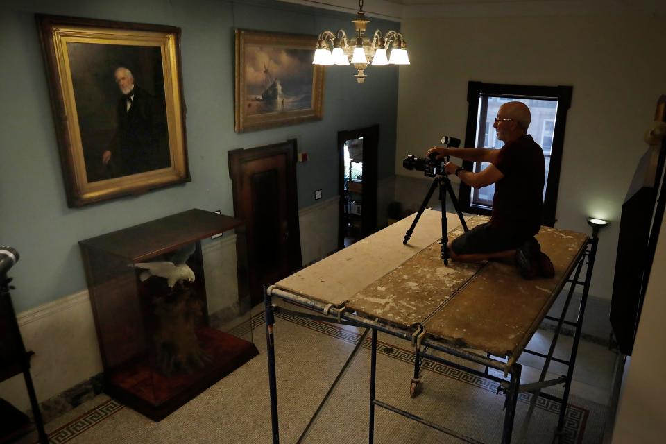 Phil Mello photographs one of the New Bedford downtown library's vast painting collection as part of an incentive by art director, Alexandra Copeland, to make the work more accessible.
