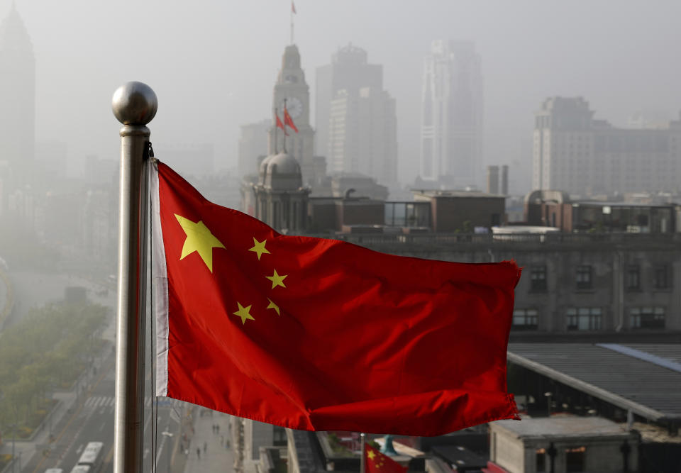 ARCHIVO - Una bandera nacional china ondea junto a edificios de oficinas en Shanghái, China, el 14 de abril de 2016. (AP Foto/Andy Wong, Archivo)