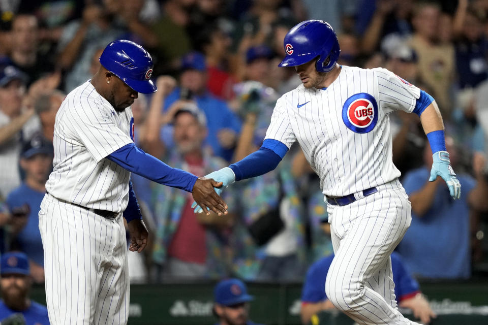 Chicago Cubs third base coach Willie Harris, left, greets Ian Happ at third after Happ's two-run home run off Washington Nationals starting pitcher MacKenzie Gore during the sixth inning of a baseball game Monday, July 17, 2023, in Chicago. (AP Photo/Charles Rex Arbogast)