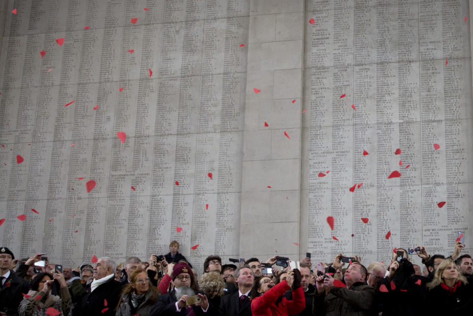 People watch as red paper poppies fall from the roof at the Menin Gate during an Armistice ceremony in Ypres, Belgium, Sunday, Nov. 11, 2018. Sunday marks exactly 100 years since the end of the First World War. (AP Photo/Virginia Mayo)