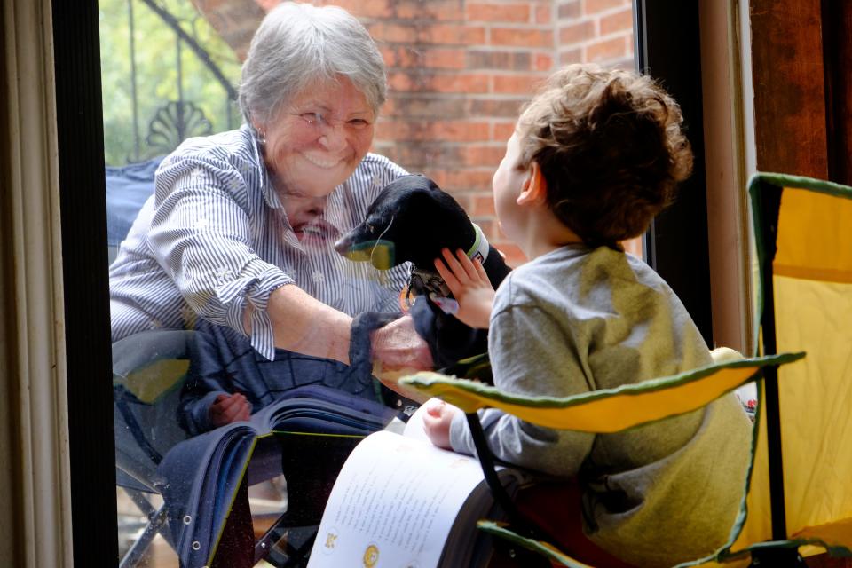 Marilyn Maitland, 72, reads to her 4-year-old grandson, Theo. When coronavirus infiltrated Austin, Texas, they had to read to each other from opposite sides of the door. Theo put his hand to the glass as if to pet his grandma's dog, Jack.