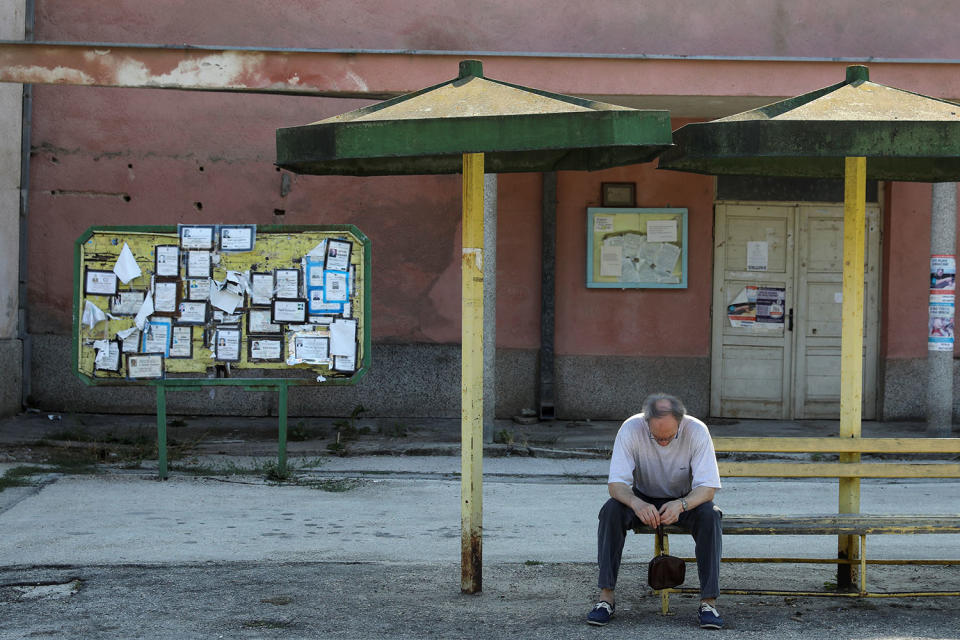 <p>Death notices are seen on a notice board as a man sits at a bus station in the village of Kalna, near the southeastern town of Knjazevac, Serbia, Aug. 15, 2017. (Photo: Marko Djurica/Reuters) </p>