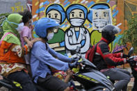 Motorists ride past a mural honoring health care workers during the new coronavirus outbreak in Jakarta, Indonesia, Thursday, May 28, 2020. (AP Photo/Dita Alangkara)