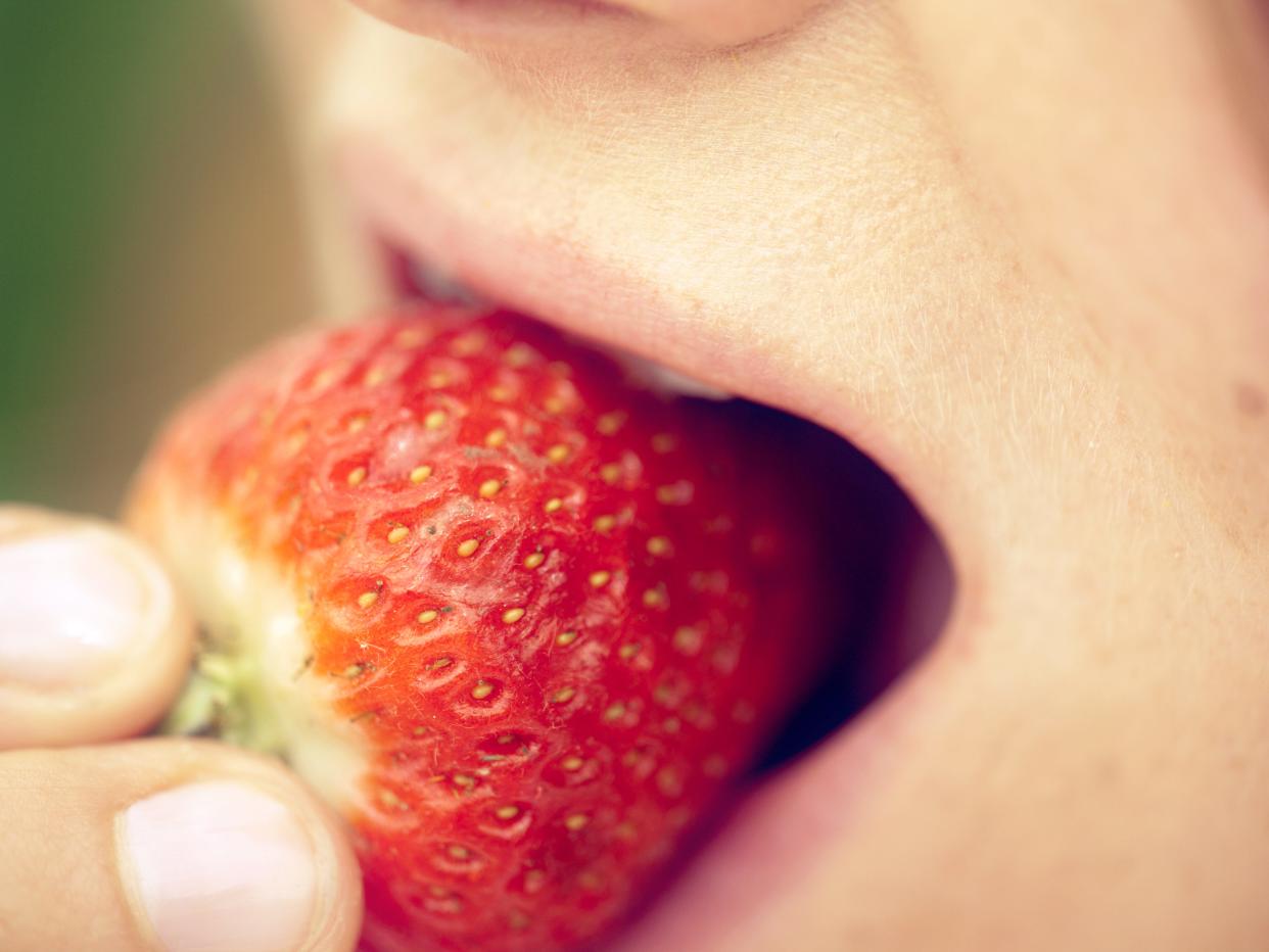 Person eating strawberry.