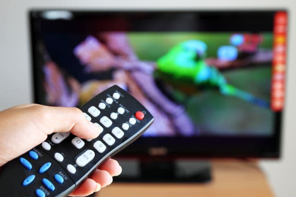 Hand pointing a tv remote control towards the television