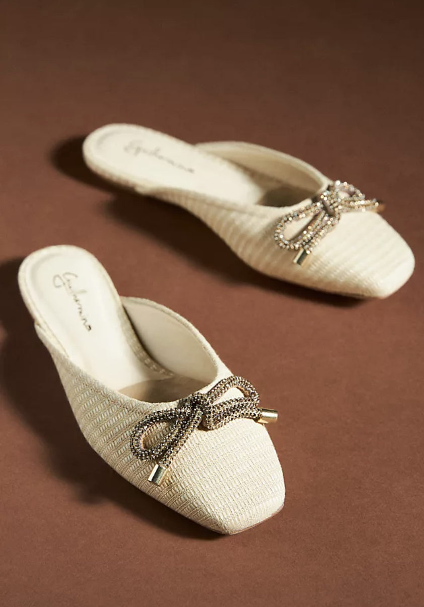 Guilhermina Ballet Mules in white with crystal bows on brown background (photo via Anthropologie)