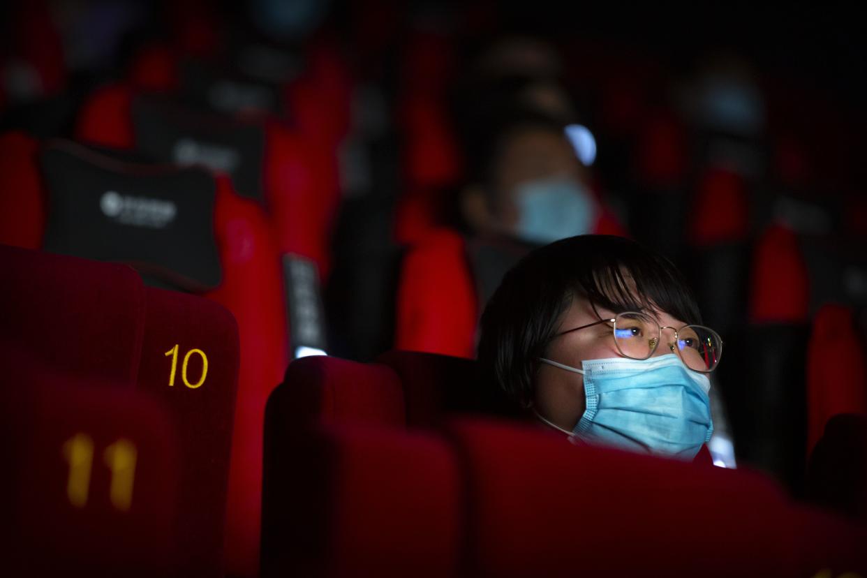 People wearing face masks to protect against the coronavirus watch a film at a movie theater in Beijing on July 24, 2020.
