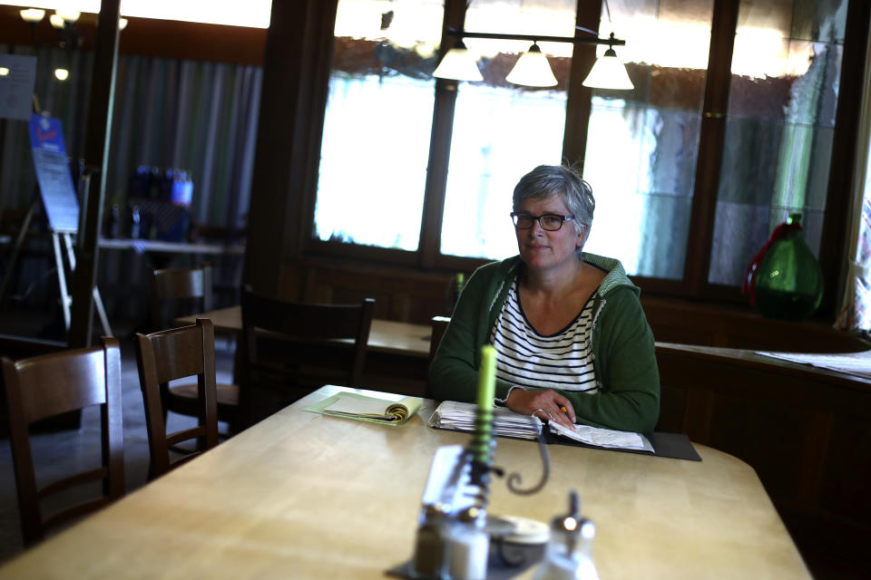 In this photo taken Friday, May 1, 2020 brewery daughter Sabine Detter sits on her accounting documentation in her 120 year old family brewery and traditional Bavarian restaurant in Altoetting, Germany. The 'Graminger Weissbraeu' brewery, which has been in the same family for a century, is preparing to welcome guests back to its restaurant for the first time in two months — with new rules and fears for the future. (AP Photo/Matthias Schrader)