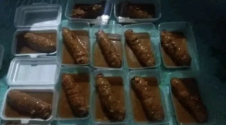 Multiple food containers, likely takeout boxes, each holding a single sausage-like food item in a brown sauce