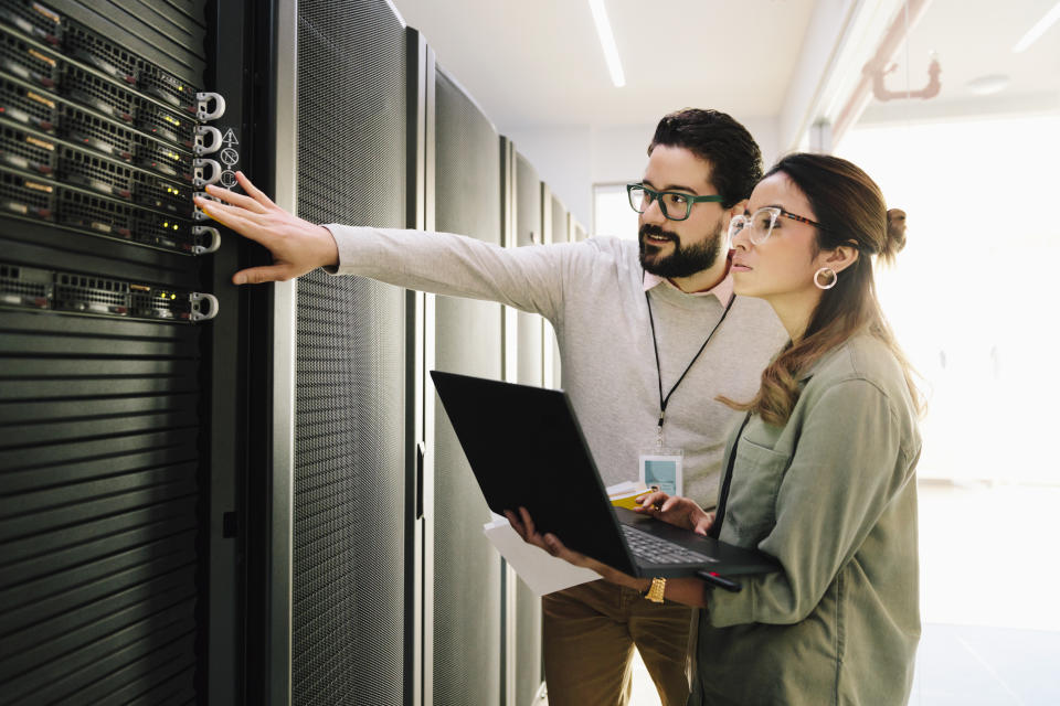 IT technicians examining equipment in network server room