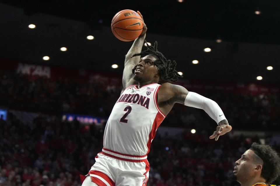 Arizona guard Caleb Love (2) goes up to dunk over Arizona State guard Jose Perez, right, during the first half of an NCAA college basketball game, Saturday, Feb. 17, 2024, in Tucson, Ariz. (AP Photo/Rick Scuteri)