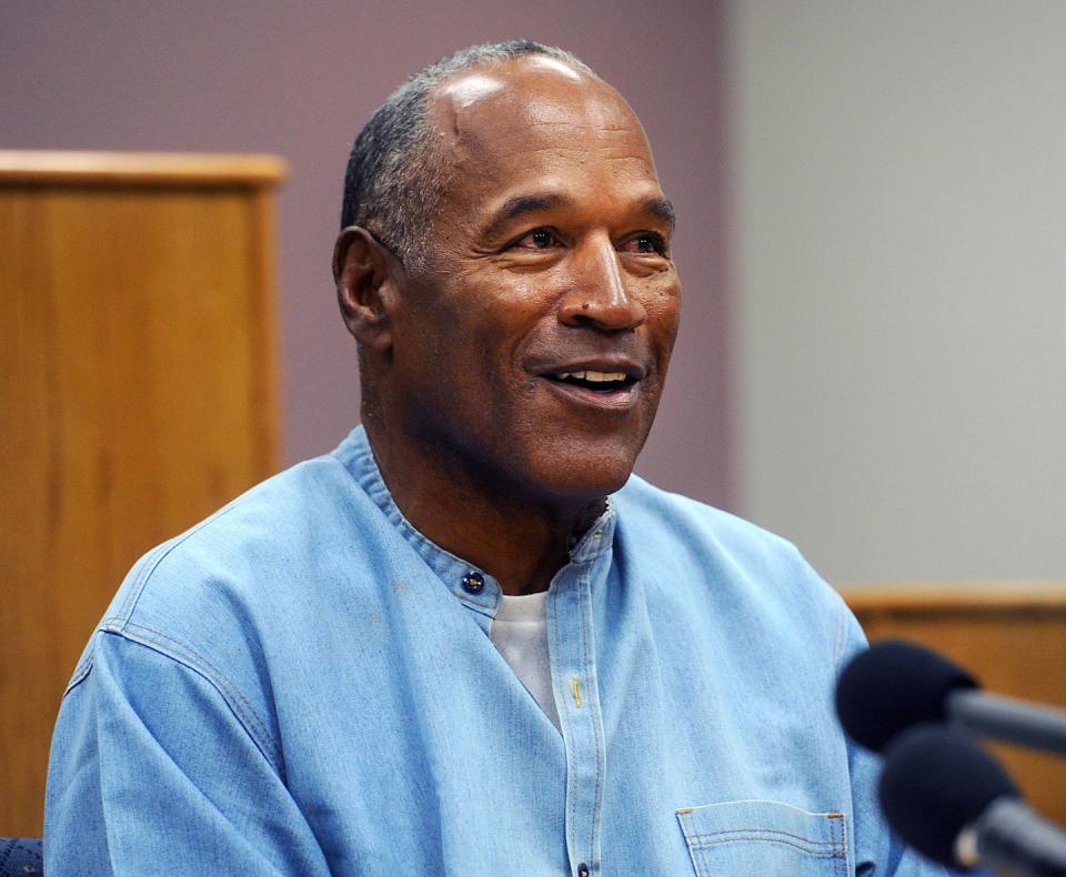 oj simpson smiles and looks to the right, he wears a denim shirt