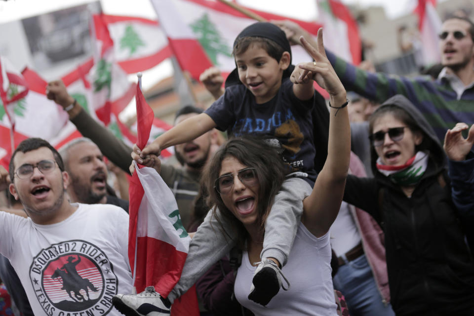 Anti-government protesters shout slogans against Lebanon's President Michel Aoun as they listen on a speaker while he addressees the nation during a protest in the town of Jal el-Dib north of Beirut, Lebanon, Thursday, Oct. 24, 2019. Aoun has told tens of thousands of protesters that an economic reform package put forth by the country's prime minister will be the "first step" toward saving Lebanon from economic collapse. (AP Photo/Hassan Ammar)