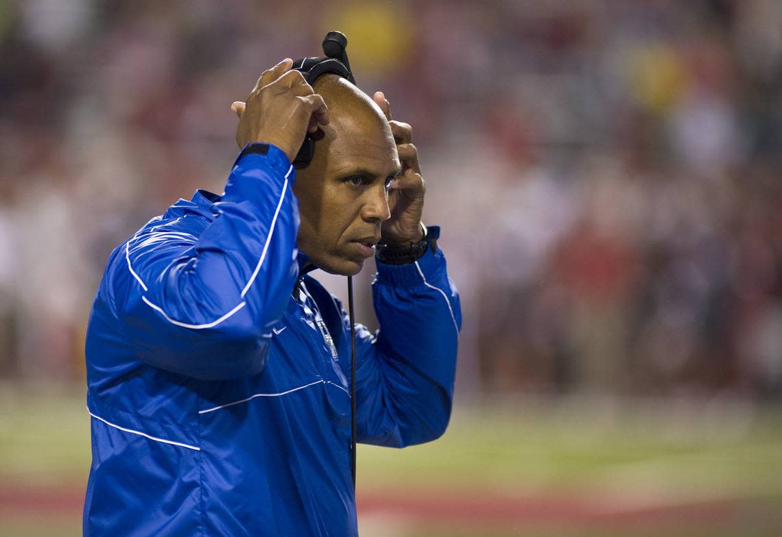 Kentucky’s Joker Phillips takes off a headset during the first half of a game against Arkansas in Fayetteville on Oct. 13, 2012.