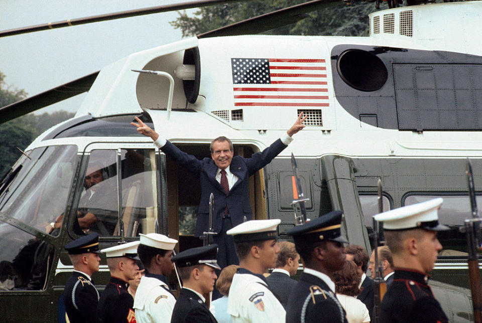 Richard Nixon giving the victory sign as he heads into a helicopter