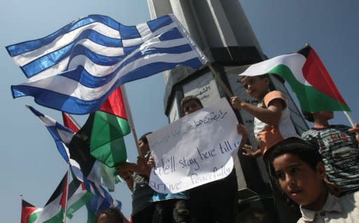 Palestinian children wave Palestinian and Greek flags during a rally in Gaza City. Greece tried to appease furious activists after halting a flotilla bound for Gaza, offering to deliver aid "through existing channels" and reaching out to the Palestinian Authority Sunday