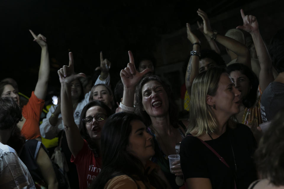 Supporters of former president Luiz Inacio Lula da Silva, who is running again for president, make an "L" sign with their hands during an interview of Lula with Jornal Nacional on TV Globo, outside a bar in Rio de Janeiro, Brazil, Thursday, August 25, 2022. Brazil's general elections are scheduled for Oct. 2. (AP Photo/Bruna Prado)