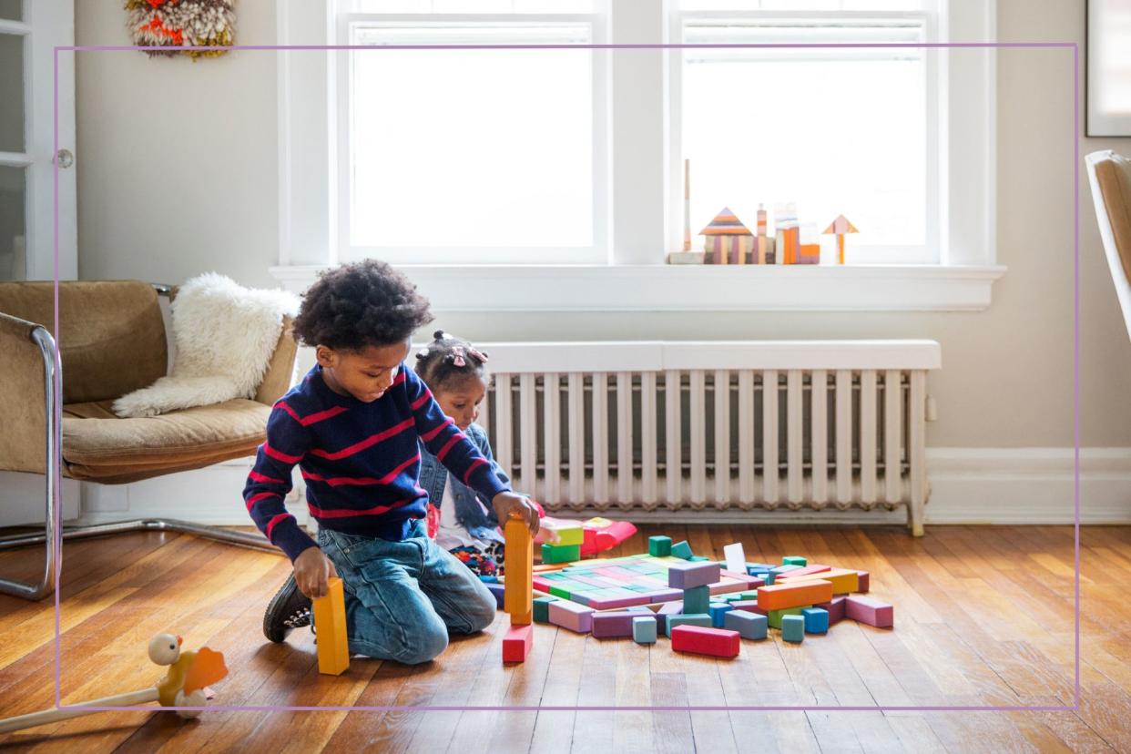  Brother and sister playing on floor at home . 