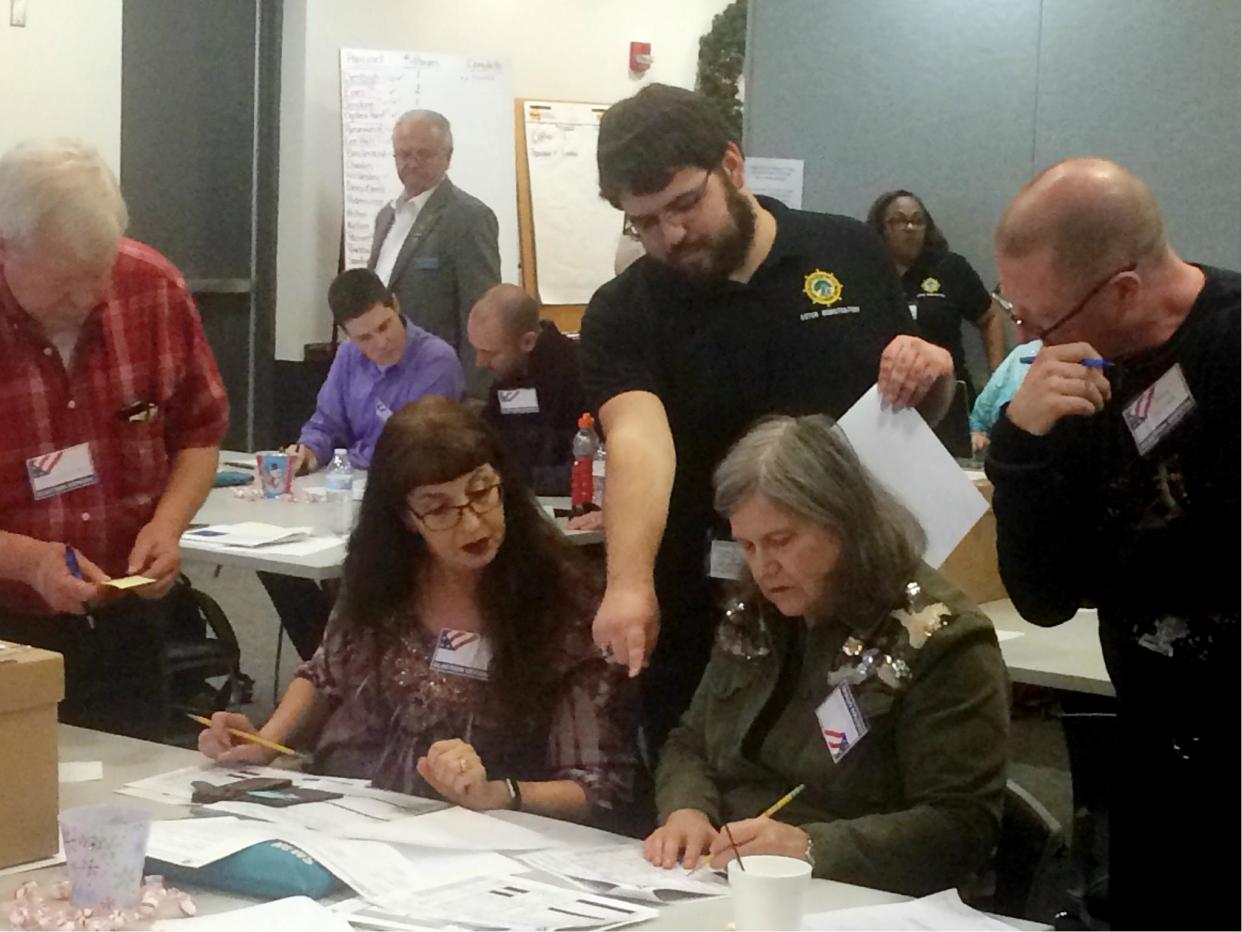 Election officials in Newport News, Virginia examine ballots that a computer failed to scan during a recount for a House of Delegates race on 19 December 2017: AP Photo/Ben Finley