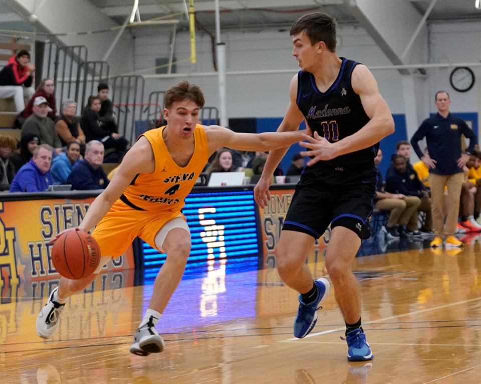 Madonna’s Brendan Young keeps Jonas Tester of Siena Heights at arm’s length as he drives Wednesday night. Madonna won 82-65.