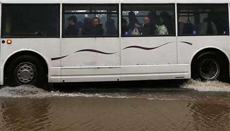 Passengers look out from a bus as it is driven through flood waters in Worcester, central England February 13, 2014. REUTERS/Darren Staples