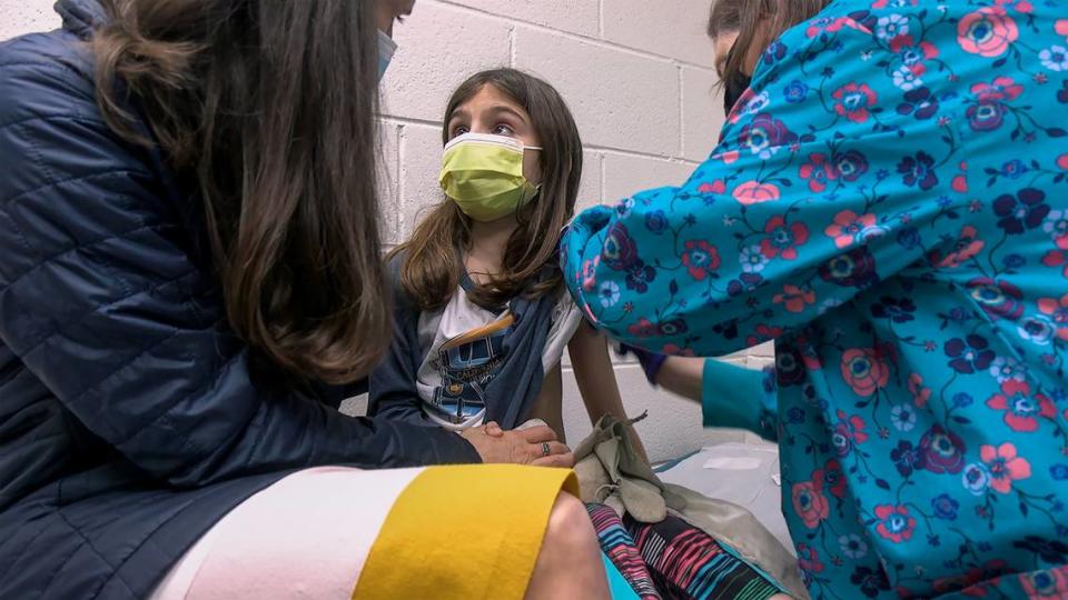 Alejandra Gerardo, 9, looks up to her mom, Dr. Susanna Naggie, as she gets the first of two Pfizer COVID-19 vaccinations during a clinical trial for children at Duke Health in Durham, North Carolina. In Kansas City, Children’s Mercy is leading the regional effort for the Pfizer trials.