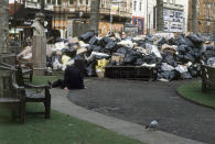 FILE - In this 1979 file photo, a man sits on the ground in front of a mound of garbage in London's Leicester Square, accumulated during a strike by council employees. The so-called Winter of Discontent that brought much of Britain to a standstill was one of the great crises in postwar Britain, the latest of which relates to its struggles to agree a way to leave the European Union. (AP Photo/John Glanville, File)