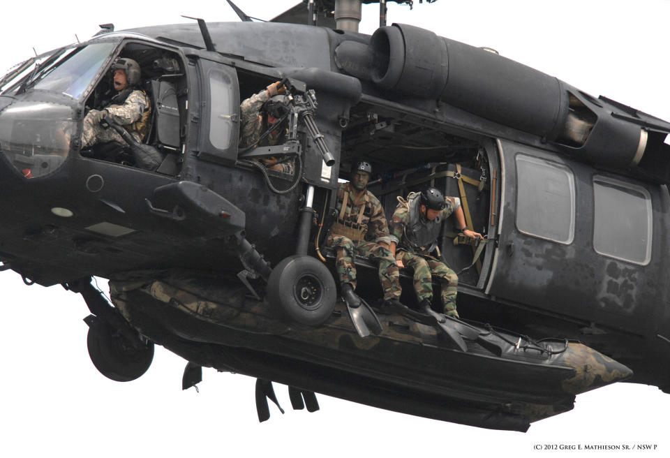 SEALs sit ready in the doorways with their Zodiac suspended below at US Army  HH-60H Seahawk belonging to the 160th Special Operations Aviation Regiment (SOAR) "NIght on Stalkers", as they prepare for a water insertion.  Photo: Greg E. Mathieson Sr. / NSW Publications, LLC