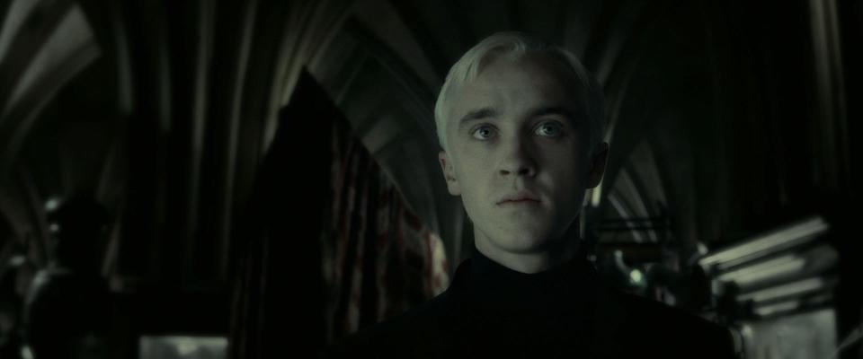 A closeup of Draco Malfoy looking pale and somber