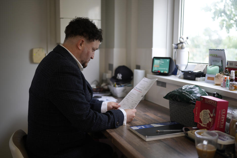 Dominic Watters, a single dad and founder of the Food is Care campaign, reads his water bills at his home in Canterbury, England, Monday, June 10, 2024. Since calling a general election, British Prime Minister Rishi Sunak has been at pains to repeat a key message on the campaign trail: The economy is turning a corner, inflation is down, and things are looking up. That’s not the reality for millions across the U.K. still feeling the squeeze from high food, energy and housing prices. (AP Photo/Kin Cheung)