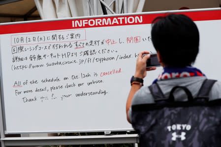 A spectator takes photos of an information board announcing the cancellation of sessions due to the approach of Typhoon Hagibis, at Formula One Japanese Grand Prix at Suzuka Circuit in Suzuka