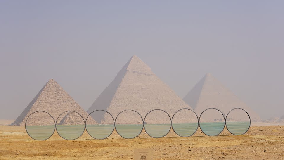 “Horizon”,<em> </em>by Greek sculptor Costas Varotsos, is a series of metal circles half-filled with glass, arranged in a line. By making it appear as if the pyramids are sitting on water, the work emphasizes the relationship between the monuments and the Nile river on the horizon behind. - Courtesy CulturVator - Art D'E